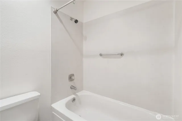 a white bath tub sitting next to a white toilet and vanity