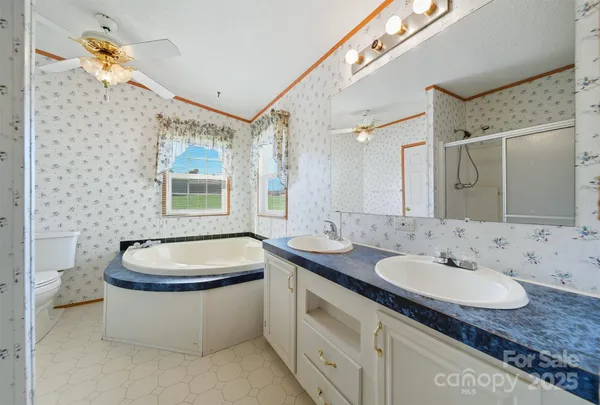 a bathroom with a granite countertop sink a toilet a mirror and shower
