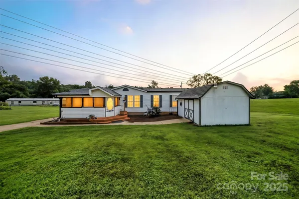 a house that is sitting in the grass with large trees