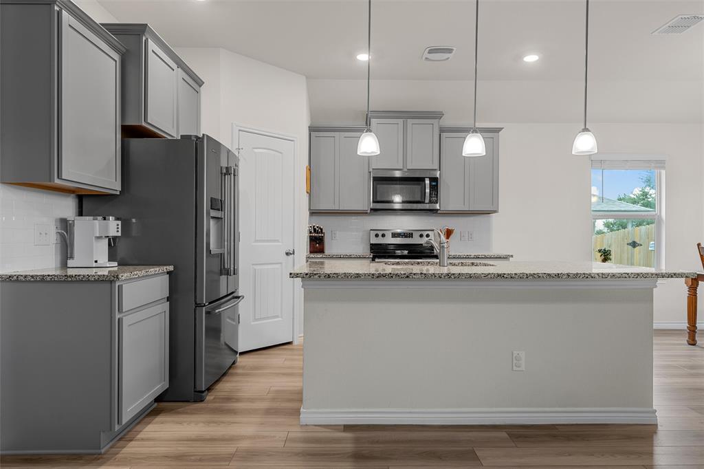 10712 Peperak Court Waco, TX 76708 - Photo 8 of 25 a kitchen with stainless steel appliances granite countertop a refrigerator a sink a stove a microwave and wooden cabinets