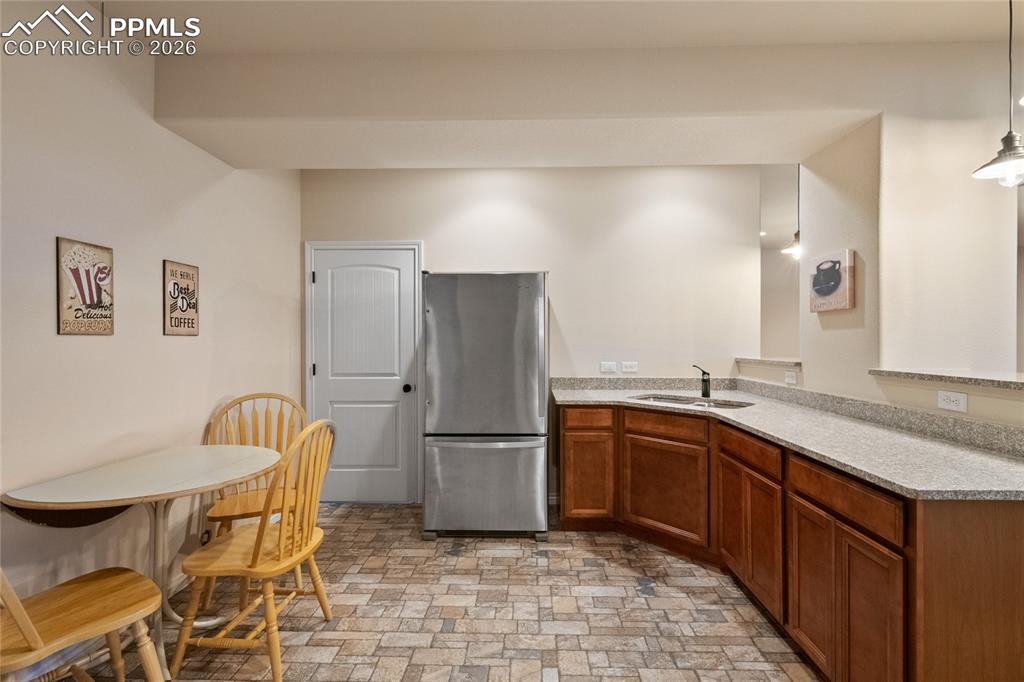 3718 Sky Rim Court Colorado Springs, CO 80908 - Photo 37 of 49 Lower level wet bar with tile flooring, granite counter, full-sized fridge, disposal and pendant lighting. Doorway into storage area.