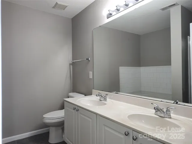 a bathroom with a granite countertop sink a toilet and a mirror