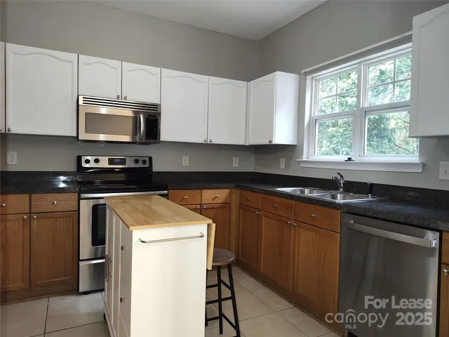 a kitchen with stainless steel appliances granite countertop a stove a sink dishwasher and a microwave oven with cabinets