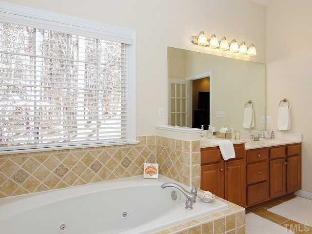 8604 Wapello Lane Raleigh, NC 27613 - Photo 16 of 25 Single French door to master bath with his-and-her dual vanity, jetted tub and separate shower with tiled surround and bench seat.