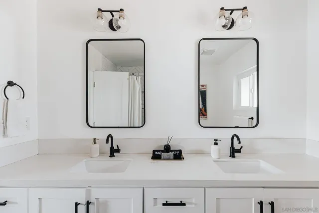 a bathroom with double vanity sink two mirror and a shower