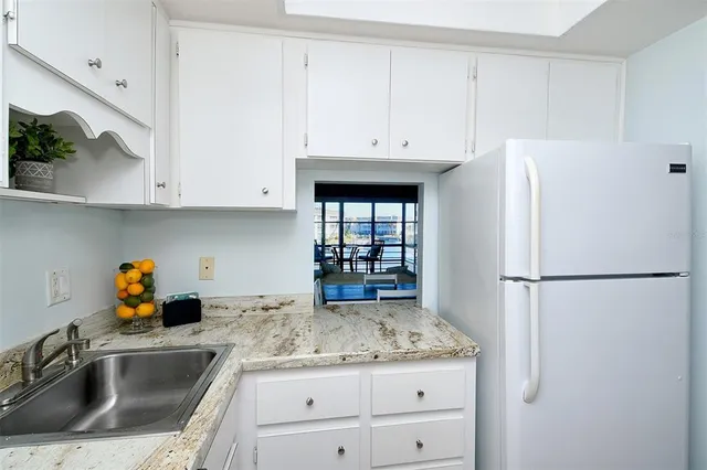 a kitchen with granite countertop a refrigerator sink and cabinets