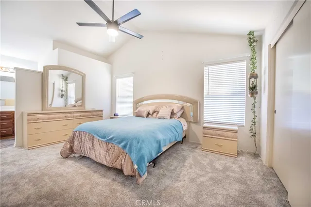 a spacious bedroom with a bed a dresser and a chandelier