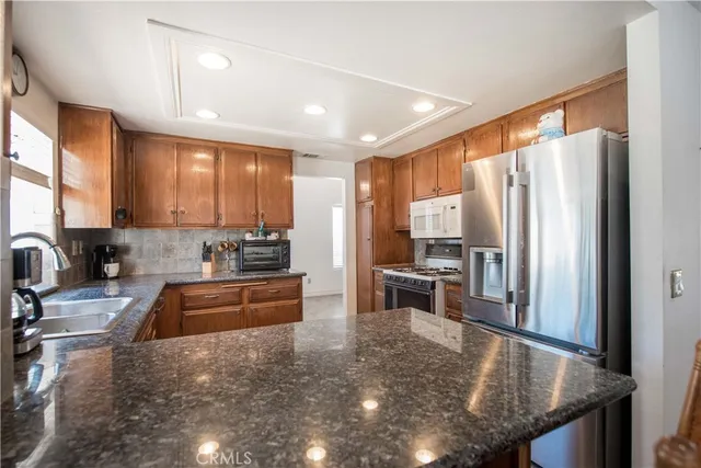 a kitchen with stainless steel appliances granite countertop a refrigerator a stove a sink a stove and island