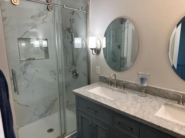 a bathroom with a double vanity sink mirror and shower