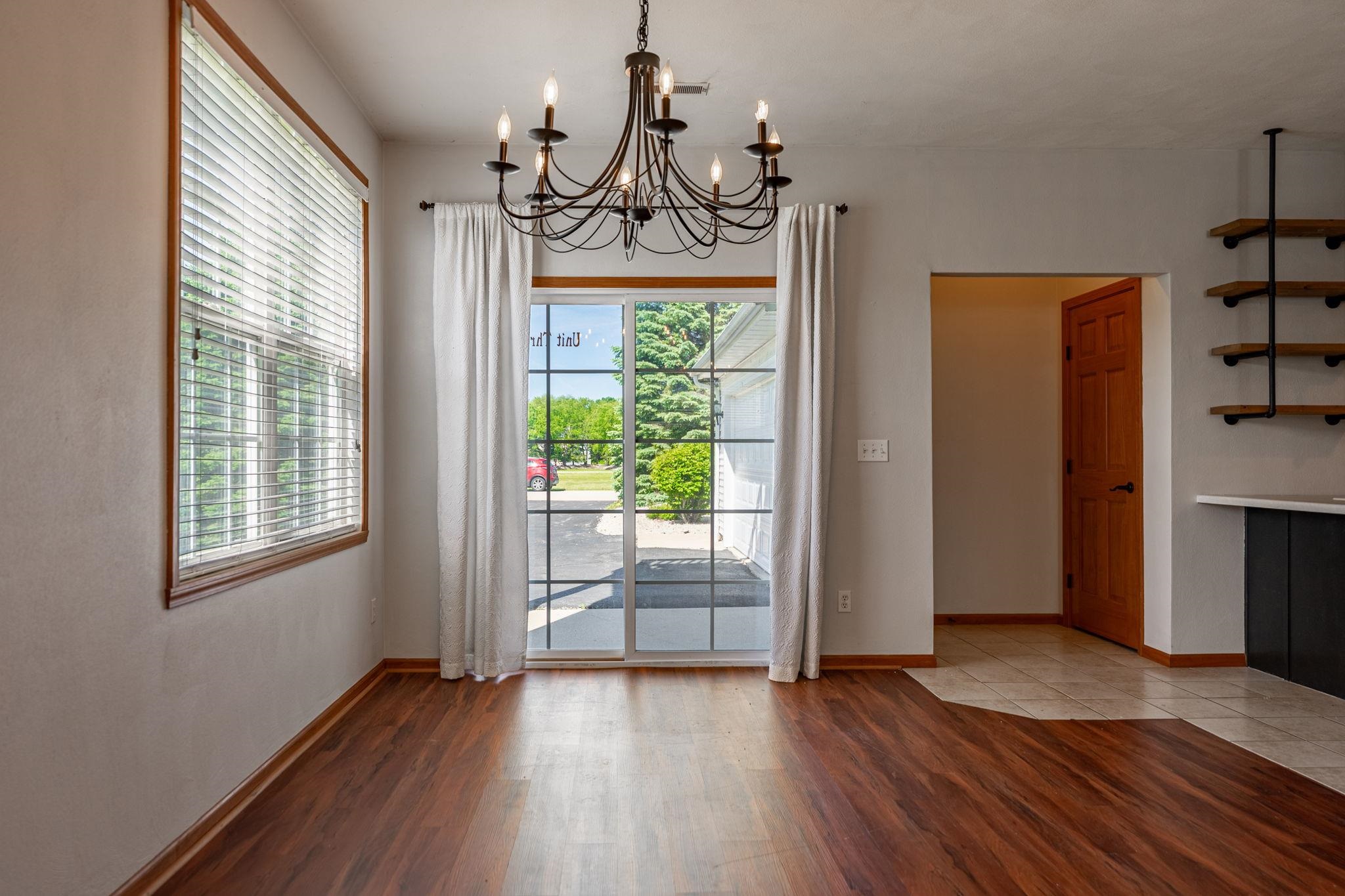 10113 Monarch Road Roscoe, IL 61073 - Photo 7 of 20 an empty room with wooden floor chandelier and windows