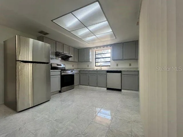 a kitchen with stainless steel appliances granite countertop a refrigerator a sink a stove a microwave and a refrigerator