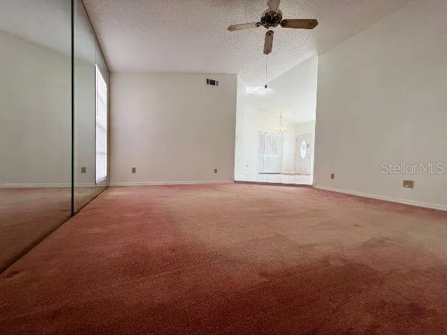 en empty room with windows and ceiling fan