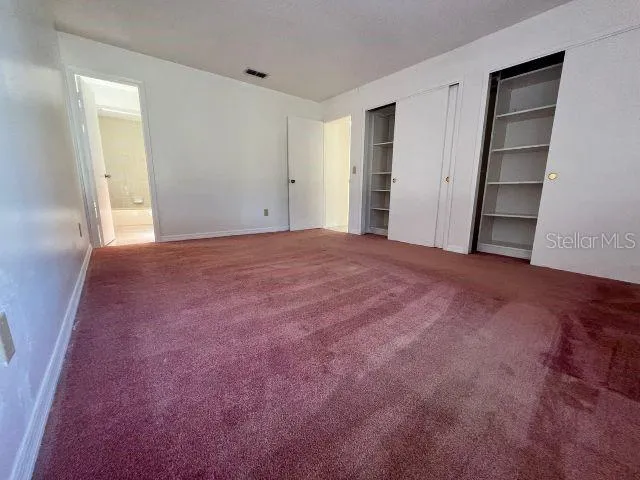 a view of an empty room with closet and kitchen