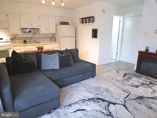 a living room with furniture and a refrigerator