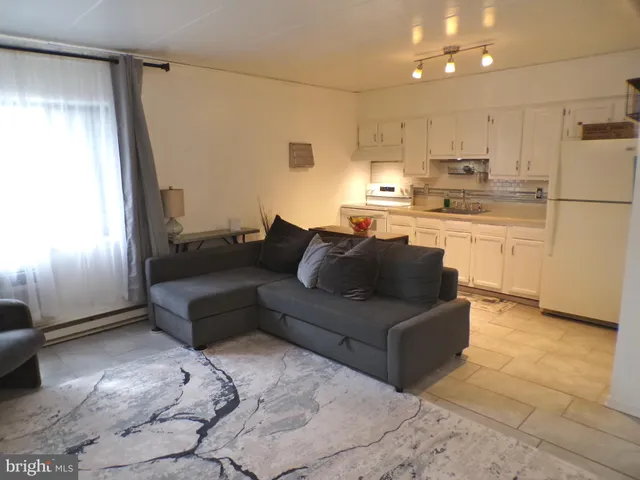 a living room with stainless steel appliances granite countertop furniture and a refrigerator