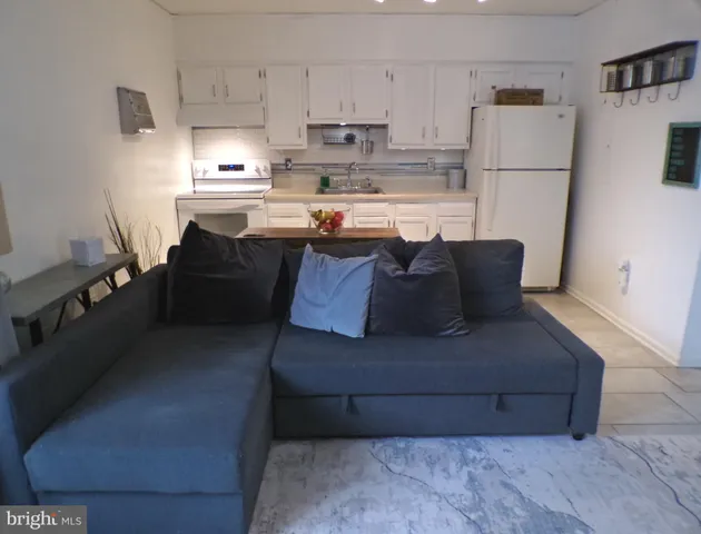 a living room with stainless steel appliances granite countertop a refrigerator sink stove and white cabinets