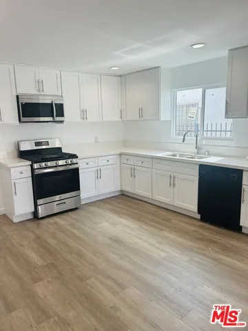 a large kitchen with granite countertop a stove top oven a sink and dishwasher