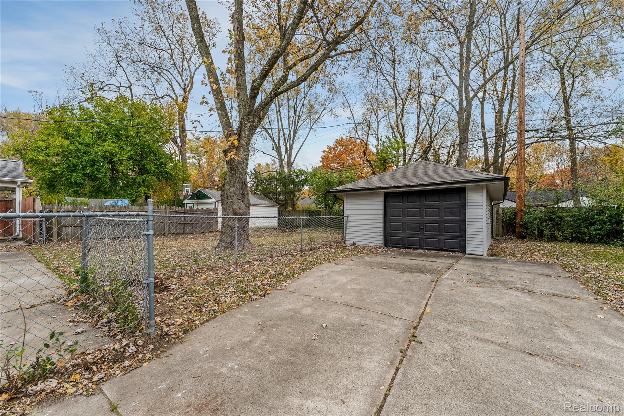 15751 West 14 Mile Road Franklin, MI 48025 - Photo 22 of 24 Detached garage with white siding and a dark garage door, accompanied by a concrete driveway