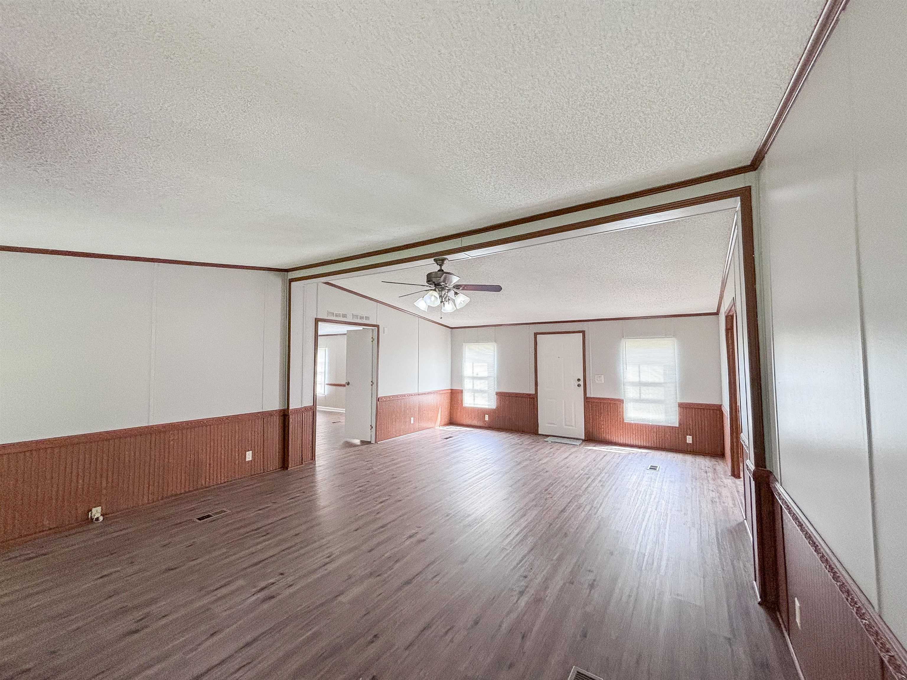 2847 Holly Grove Road Covington, TN 38019 - Photo 8 of 36 Spacious living area featuring wood-finish flooring, white paneling, and a wood-tone wainscot
