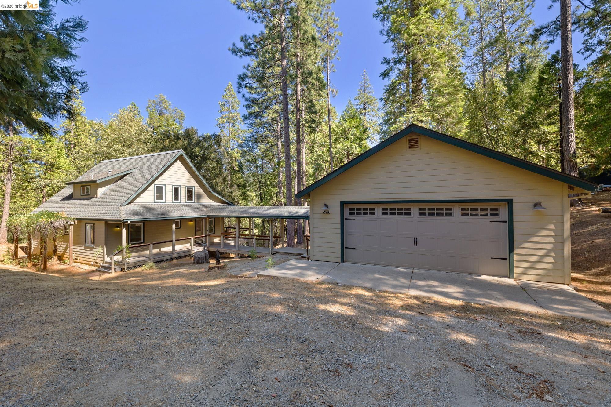 a view of a house with large trees and wooden fence