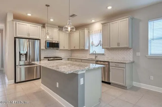 a kitchen with kitchen island granite countertop a sink appliances cabinets and counter space