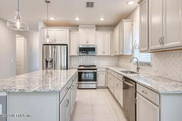 a kitchen with kitchen island granite countertop stainless steel appliances and white cabinets