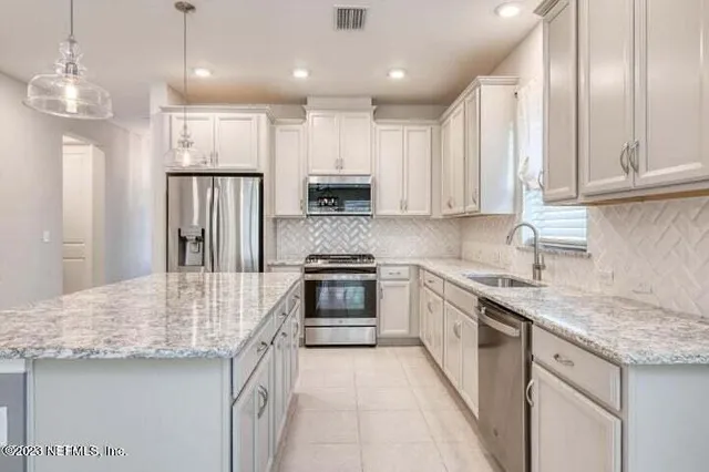 a kitchen with kitchen island granite countertop stainless steel appliances and white cabinets