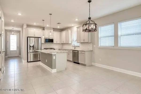 a kitchen with stainless steel appliances granite countertop a refrigerator a sink dishwasher a stove and white cabinets with wooden floor