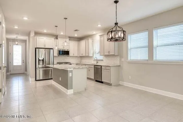 a kitchen with stainless steel appliances granite countertop a refrigerator a sink dishwasher a stove and white cabinets with wooden floor