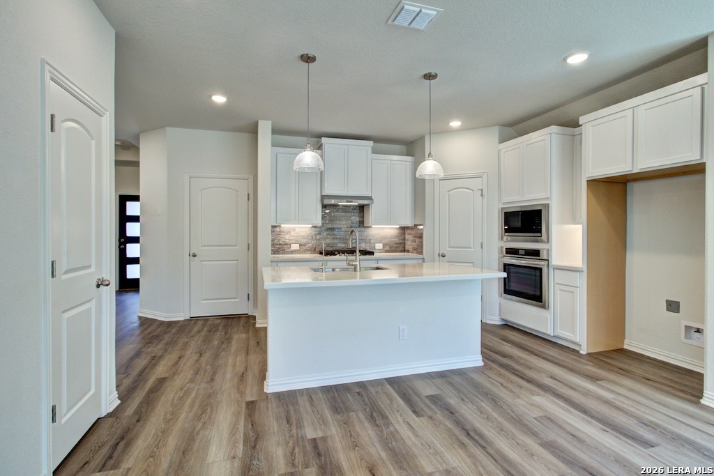 11234 Prairie Landing Converse, TX 78109 - Photo 4 of 6 a large kitchen with a center island wooden floor stainless steel appliances and a window