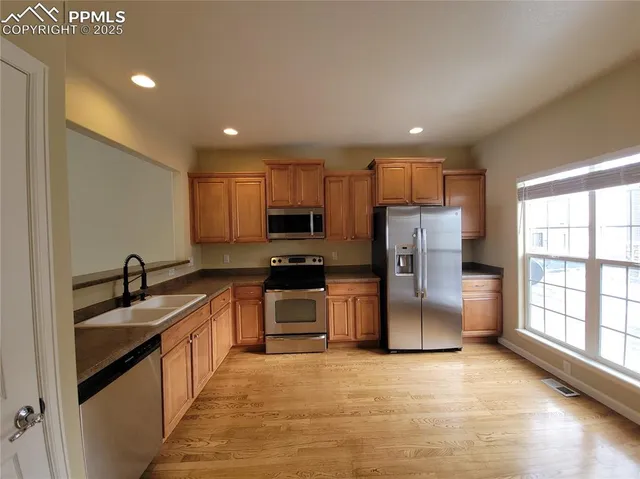 a kitchen with stainless steel appliances granite countertop a refrigerator sink and stove