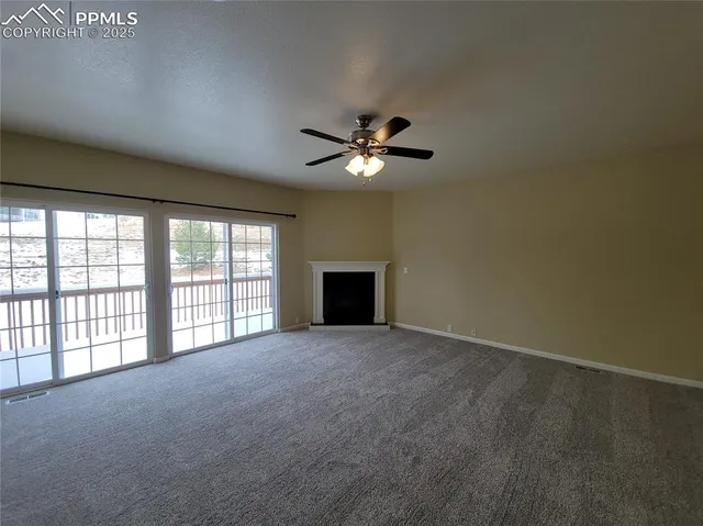 an empty room with a ceiling fan and windows
