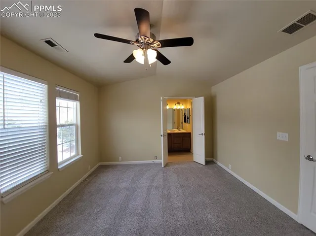 a view of an empty room with a window and a kitchen