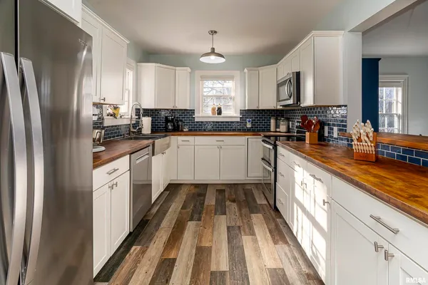 a large kitchen with stainless steel appliances granite countertop a refrigerator a sink dishwasher a stove and white countertops with wooden floor
