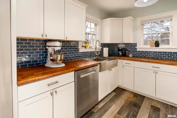 a kitchen with stainless steel appliances granite countertop white cabinets sink and window