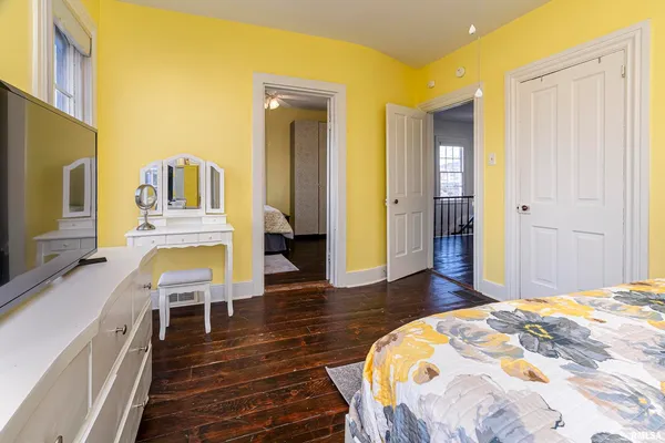 a spacious bedroom with a bed and a flat tv screen on dresser