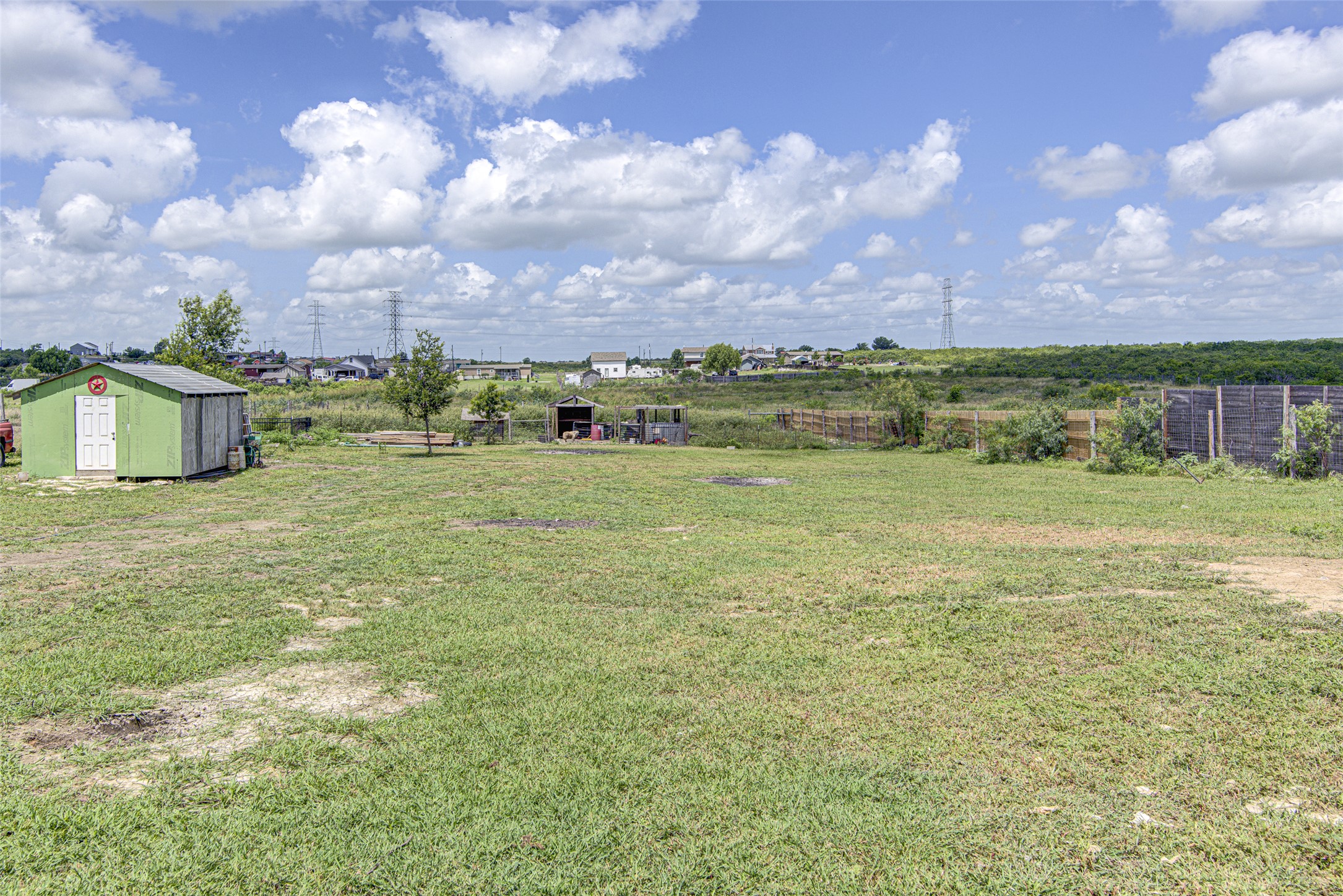 445 Rancho Linda Drive Lockhart, TX 78644 - Photo 8 of 26 A green shed sits on a spacious yard, offering utility and ample open space under an expansive sky.