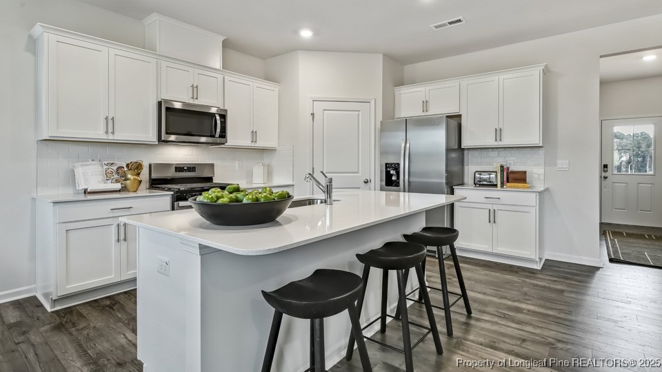 45 Mercer Way Spring Lake, NC 28390 - Photo 11 of 35 a kitchen with stainless steel appliances a sink a stove a refrigerator cabinets and wooden floor