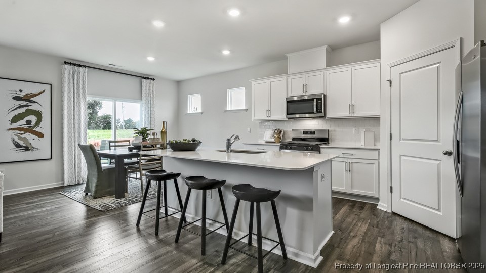 45 Mercer Way Spring Lake, NC 28390 - Photo 8 of 35 a kitchen with stainless steel appliances granite countertop a stove a sink a microwave a refrigerator and white cabinets with wooden floor