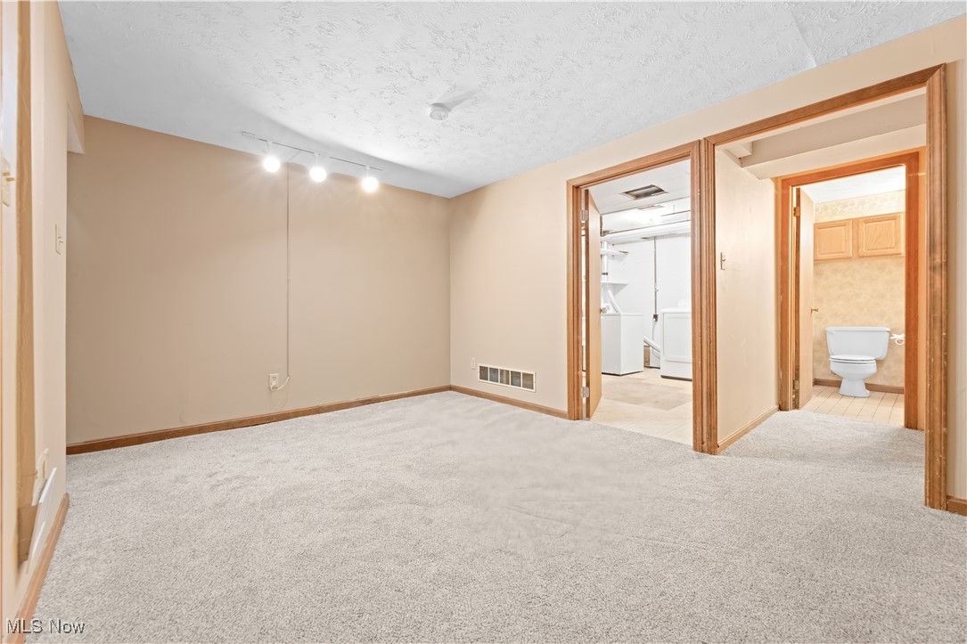 1574 Faye Road Akron, OH 44306 - Photo 27 of 45 Unfurnished bedroom with washer / dryer, a textured ceiling, ensuite bathroom, and light colored carpet