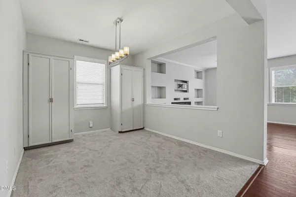 an empty room with chandelier fan and windows