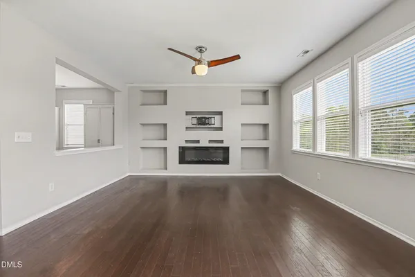 a view of an empty room with a window and wooden floor