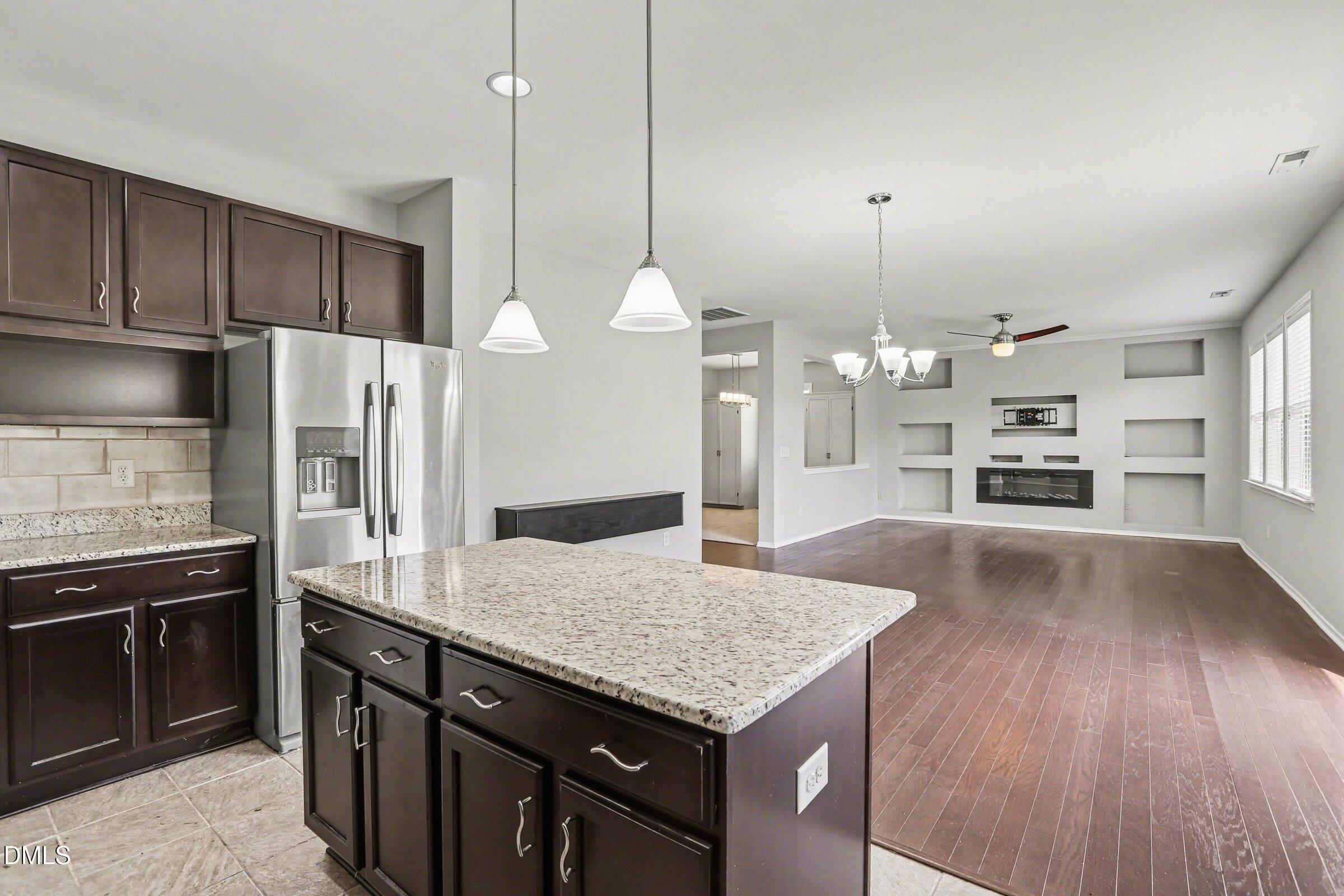 132 Daneborg Road Durham, NC 27703 - Photo 21 of 37 a kitchen with granite countertop a stove a kitchen island a sink dishwasher a refrigerator and wooden floor