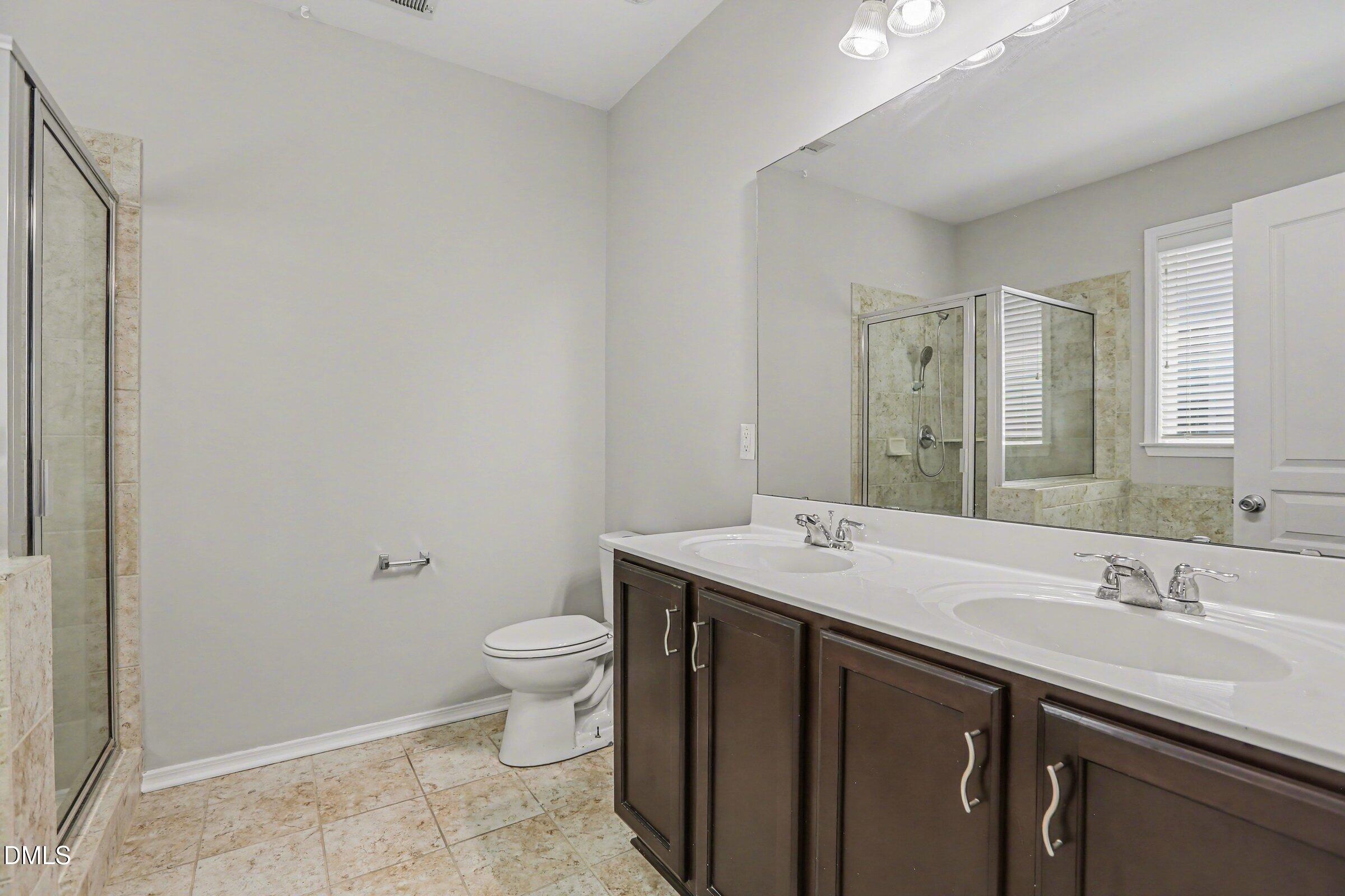 132 Daneborg Road Durham, NC 27703 - Photo 29 of 37 a bathroom with a sink a toilet a mirror and vanity