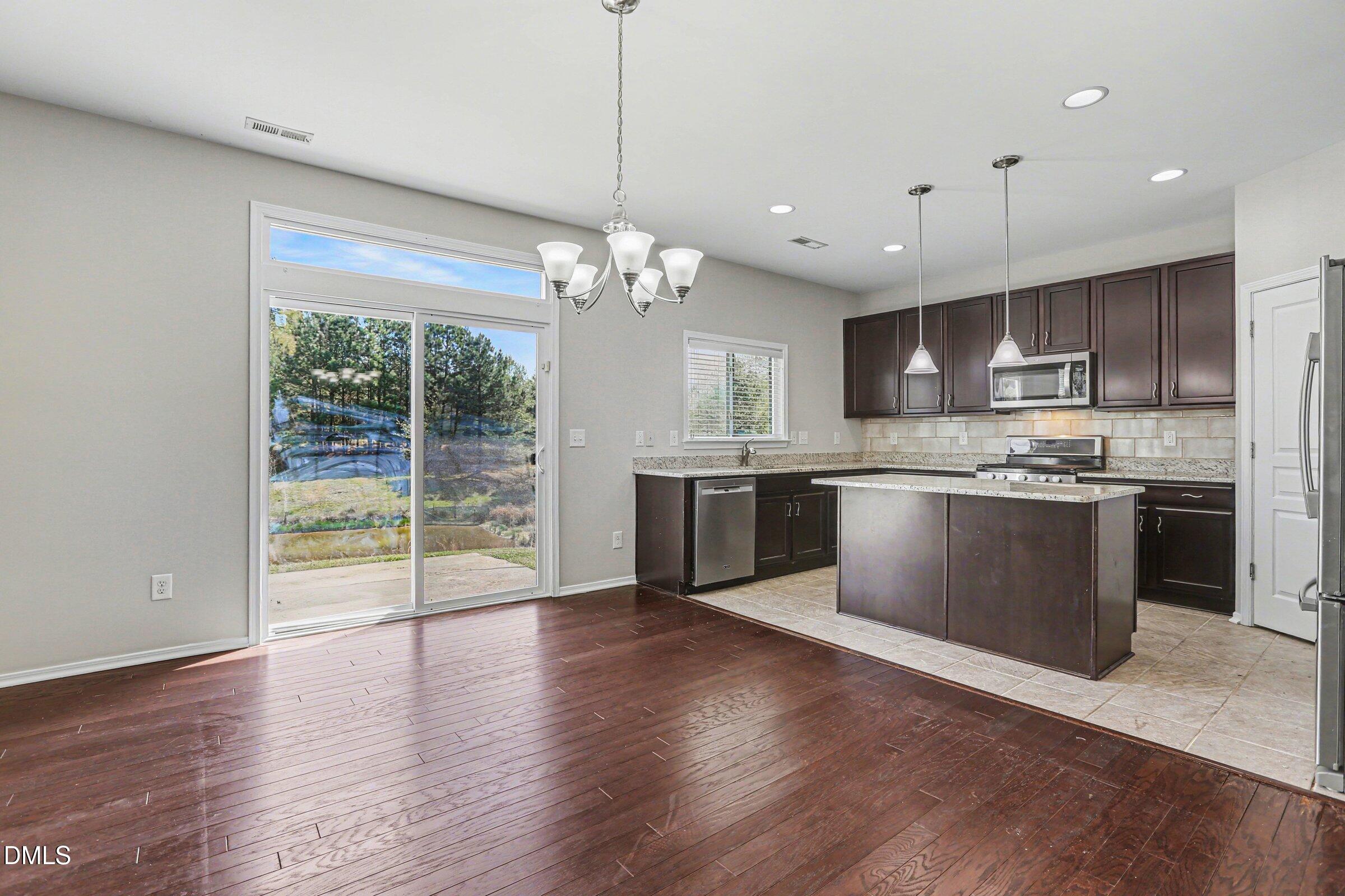 132 Daneborg Road Durham, NC 27703 - Photo 5 of 37 a kitchen with stainless steel appliances granite countertop a stove top oven a sink with wooden floors and cabinets