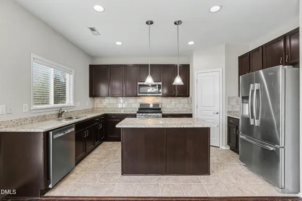 a kitchen with stainless steel appliances granite countertop a stove a sink a refrigerator and a microwave
