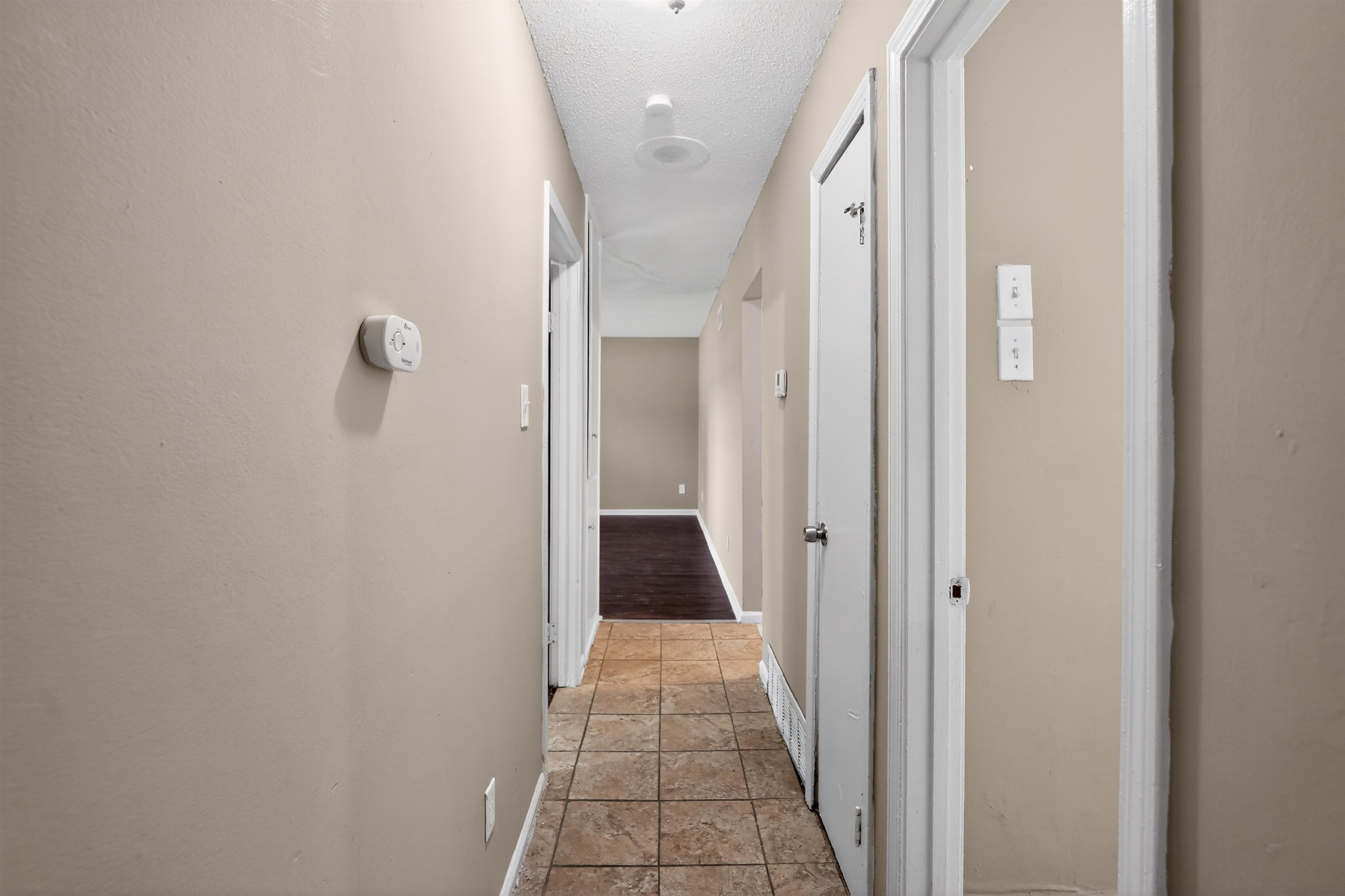 3608 Cane Ridge Drive Memphis, TN 38109 - Photo 31 of 31 Hallway featuring neutral wall tones, square tile flooring, white trim, and doors with silver hardware