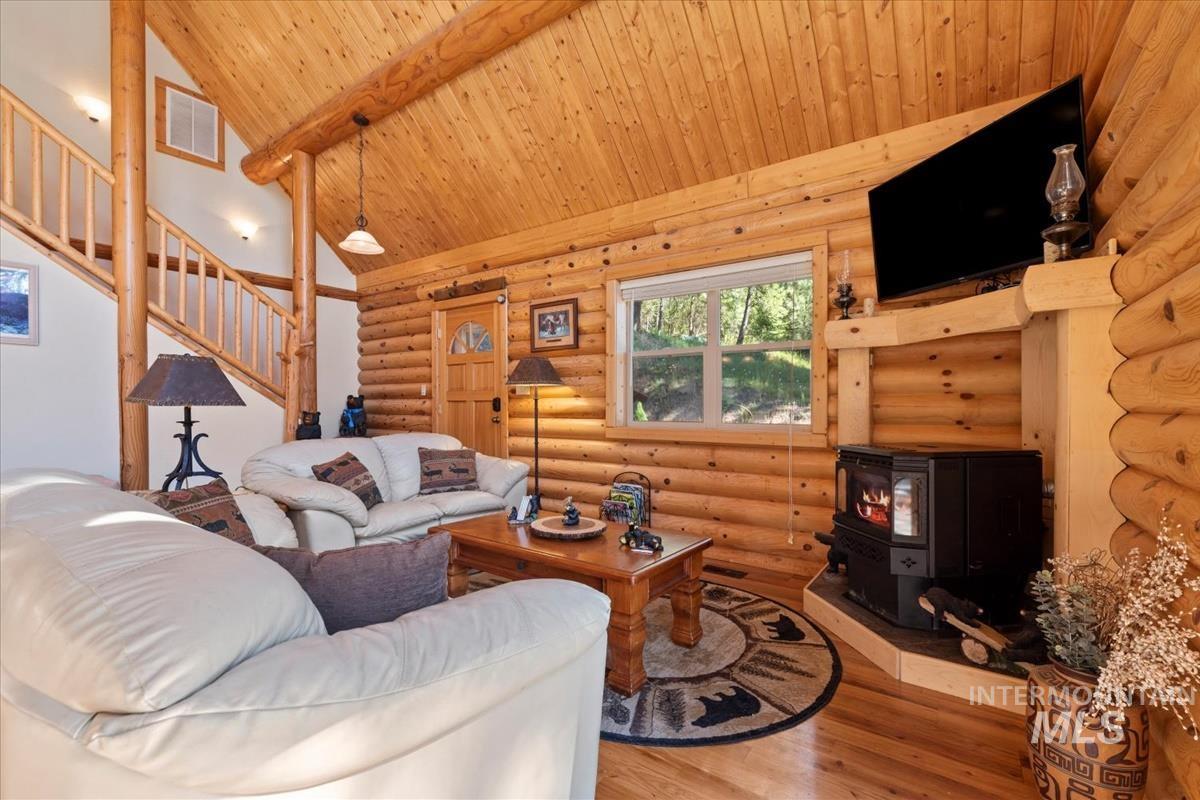 10 Elk Point Road Garden Valley, ID 83622 - Photo 10 of 42 Living room featuring a wood stove, wood finished floors, log walls, and a high wooden beamed ceiling