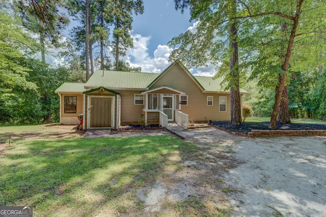 a view of a house with a yard and large tree
