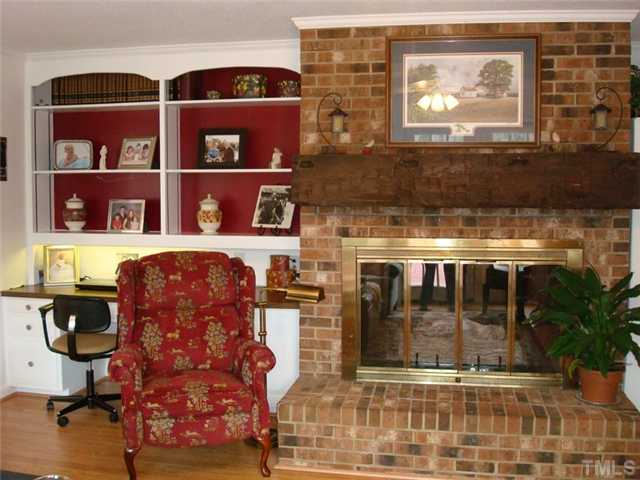 7905 Hollander Place Raleigh, NC 27606 - Photo 18 of 25 Masonry fireplace has gas log insert. Built-ins with desk for computer.
